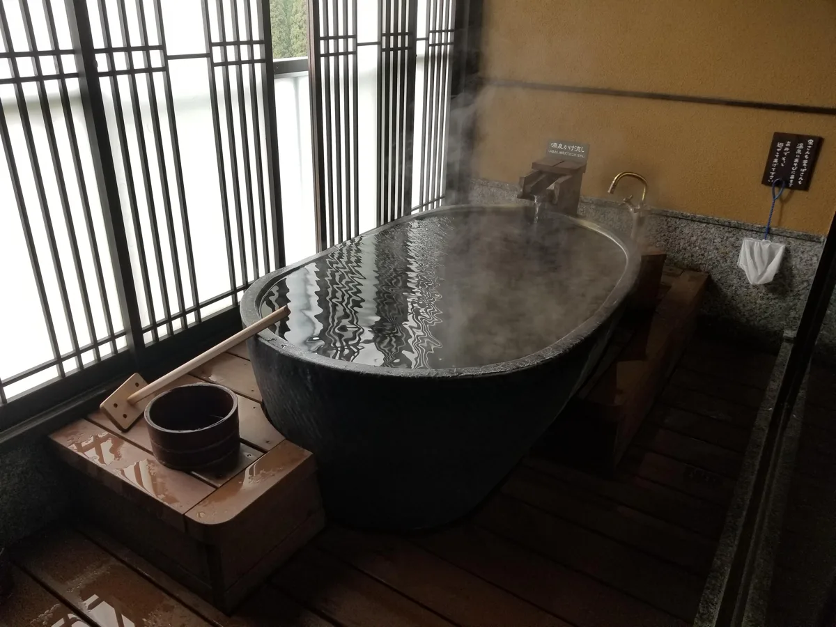 ふくみつ華山温泉の露天風呂付き客室。湯けむりの立つ陶器の湯船